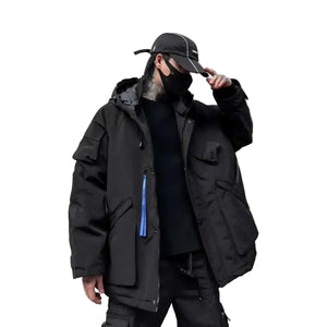 Person wearing a black coat and cap against a gray wall