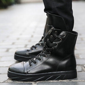 Black high top techwear boots worn on a paved street, glossy finish and folded collar