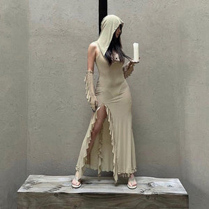 Woman standing on a wooden block in the Hooded Cut Out Dress, holding a candle, ruffled slit and sandals