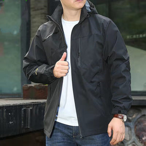 Man wearing the black hooded shell jacket open over a white tee, front three-quarter view, thumb up