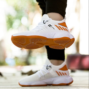 White knit sneakers in mid-step, orange outsole with a round tread pattern seen from below