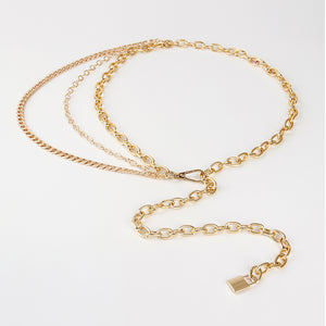 Goudkleurige tailleketting met meerdere lagen plat neergelegd, drie kettingstrengen en een hangslothanger aan de langste ketting