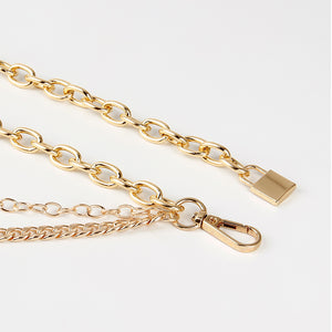 Close-up van de goudkleurige kettingriem met de hangslothanger, de karabijnhaak en de platte gourmetketting