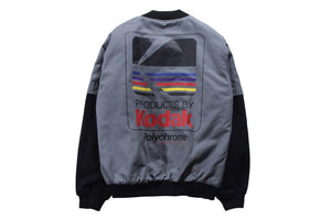 Grey layered sleeve baseball bomber jacket laid flat, back view with the print and black sleeves