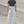 Back view of the light wash baggy jeans on a model, black spiked emblem on the back pocket, loose legs