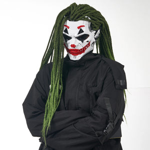 Person wearing a white mask with red accents and green dreadlocks, dressed in black clothing.