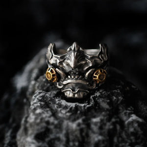 Antiqued metal ring shaped as a horned oni mask with gold accents