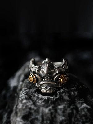 Antiqued metal ring shaped as a horned oni mask with gold accents