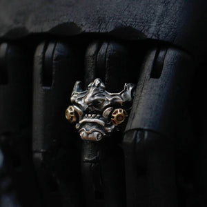 Antiqued metal ring shaped as a horned oni mask with gold accents