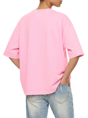 Pink acid wash tee in a back three-quarter view on a model, loose boxy fit falling over light jeans