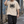 Man in the Light Apricot oversized graphic tee and black pants walking down a street, hand in his hair