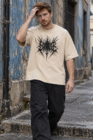 Man in the Light Apricot oversized graphic tee and black pants walking down a street, hand in his hair
