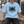 Man sitting on a low wall in the Sky Blue oversized acid wash tee, front view of the black thorn artwork