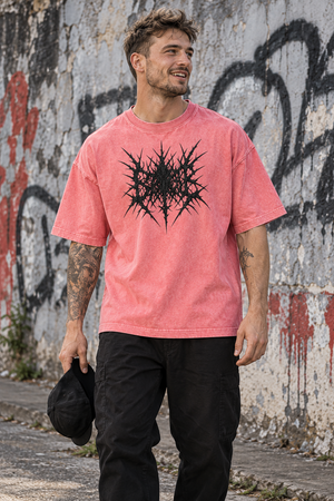 Man in the Pink acid wash graphic tee holding a cap by a graffiti wall, front view of the oversized fit