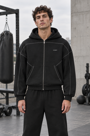 Man wearing the Oversized Black Zip Up Hoodie zipped up outdoors, front view with matching black sweatpants
