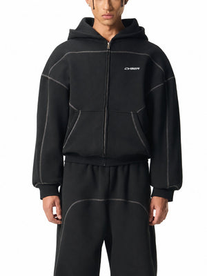 Front view of the black oversized zip hoodie on a model, grey contrast stitching around the front pockets
