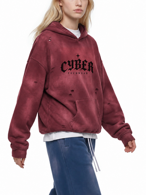 Kobieta idąca w bluzie z efektem wyblakłego słońcem w kolorze ciemnej czerwieni, widok z przodu na nadruk CYBER i postrzępione dziury
