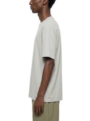 Sidevisning af en mand i den lysegrå oversized T-shirt, der viser den nedfaldne skuldersøm og den løse pasform