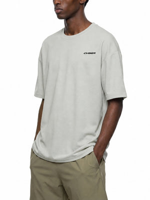 Mand i den lysegrå oversized T-shirt set på skrå, hånd i lommen, CYBER-tryk på brystet