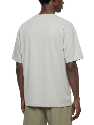 Lysegrå oversized T-shirt set på skrå bagfra på en model, brede ærmer og lige kant