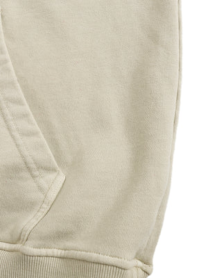 Close-up of the Apricot hoodie kangaroo pocket opening and side seam, with stitched edges above the ribbed hem