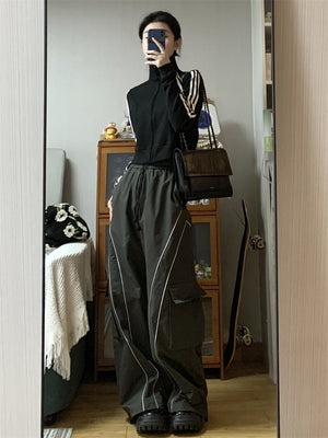 Selfie en el espejo con los pantalones de pernera ancha gris carbón con un bolsillo cargo en el muslo, combinados con una chaqueta negra con cremallera
