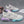 Pair of Cotton Candy basketball sneakers on grey carpet, cream upper with lilac and mint sole