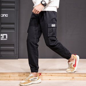 Black Patch Pocket Techwear Joggers on a man walking, side view of the thigh cargo pocket and the ankle cuffs