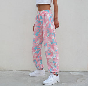 Side view of the Pink Camo Y2K Sweatpants with a white crop top, baggy leg cuffed above white sneakers