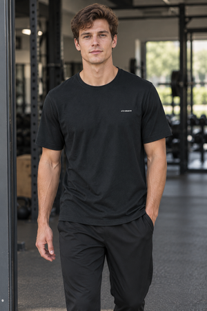 Man walking in a gym in the Black regular fit gym tee, front view with black training pants
