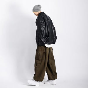 Side view of the oversized black PU leather jacket with wide brown cargo pants and white sneakers