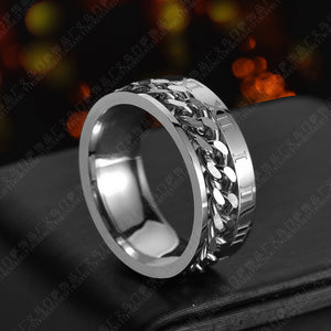 Roman Chain Techwear Ring in silver-tone, side view of the chain band against a blurred warm background