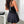 Ruched Bandeau Y2K Dress in black, back view with a black shoulder bag over the layered skirt