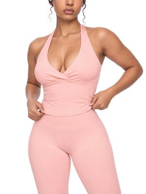Model wearing the pink Ruched Halter Yoga Tank Top, front view with a plunging V neck and a twist across the bust