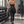 Model walking through a gym in the black ruched halter top, halter strap and open back, dumbbell rack behind