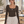 Front view of the Coffee bodysuit worn in a pilates studio, small white chest logo and thumb holes at the cuffs