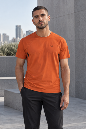 Orange running t-shirt on a man outdoors, front view with crew neck and small dark chest logo