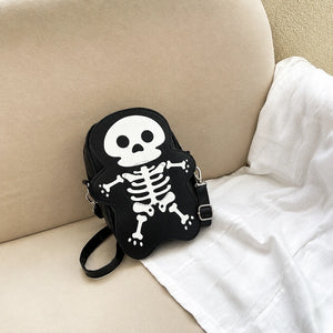 Black, beige and hot pink skeleton purses lined up on a sofa, white skull and bones design on each one