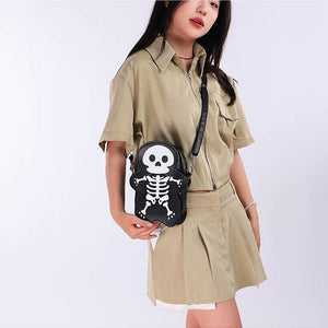Model in khakifarbenem Hemd und Faltenrock mit der schwarzen Skelett-Umhängetasche vorn, weißes Totenkopf-Design