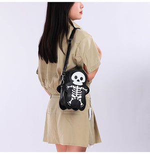 Modella in abito chemisier cachi con la borsa skeleton nera a tracolla, vista laterale del disegno scheletro bianco