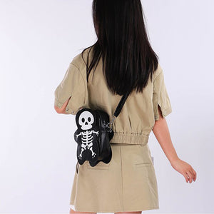 Vista posteriore di una modella in outfit cachi con la borsa skeleton nera sul fianco e la tracolla in diagonale