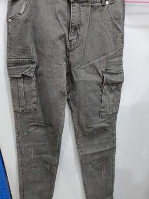 Gray cargo jeans on a hanger, close view of the zip fly, side flap pockets and light distressed marks