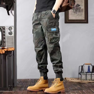 Front view of the army green Slim Camo Cargo Pants, hands in pockets, tapered cuffs over tan boots