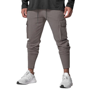 Dark Gray Slim Fit Techwear Joggers on a man in a dark top, front view of the tapered leg and white running shoes