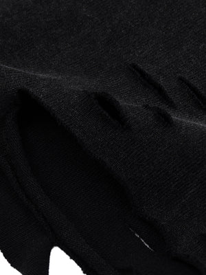 Close-up of the torn hem, the knit cut open in slashes rather than finished with a seam