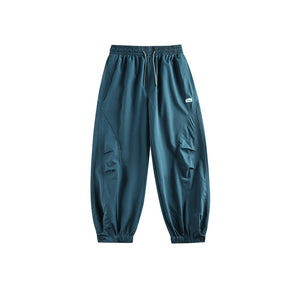 Teal blue drawstring pants laid flat, front view, small patch label on the hip and elastic ankle cuffs