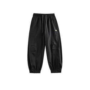 Black cyberpunk pants laid flat, front view with white drawstring, knee pleats and cuffed hems
