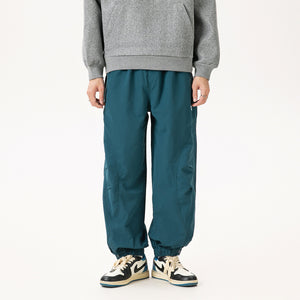 Teal blue pants worn with a grey hoodie and sneakers, front view, relaxed leg gathered at the ankle