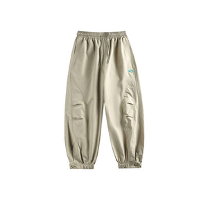 Khaki pants laid flat, front view with elastic waist, curved panel seams and gathered ankle cuffs