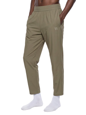 Khaki athletic pants in three-quarter front view, hand in the slash pocket, small logo on the left thigh